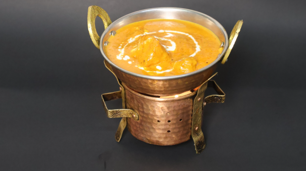 Creamy Butter Chicken served in a traditional copper bowl on a warmer