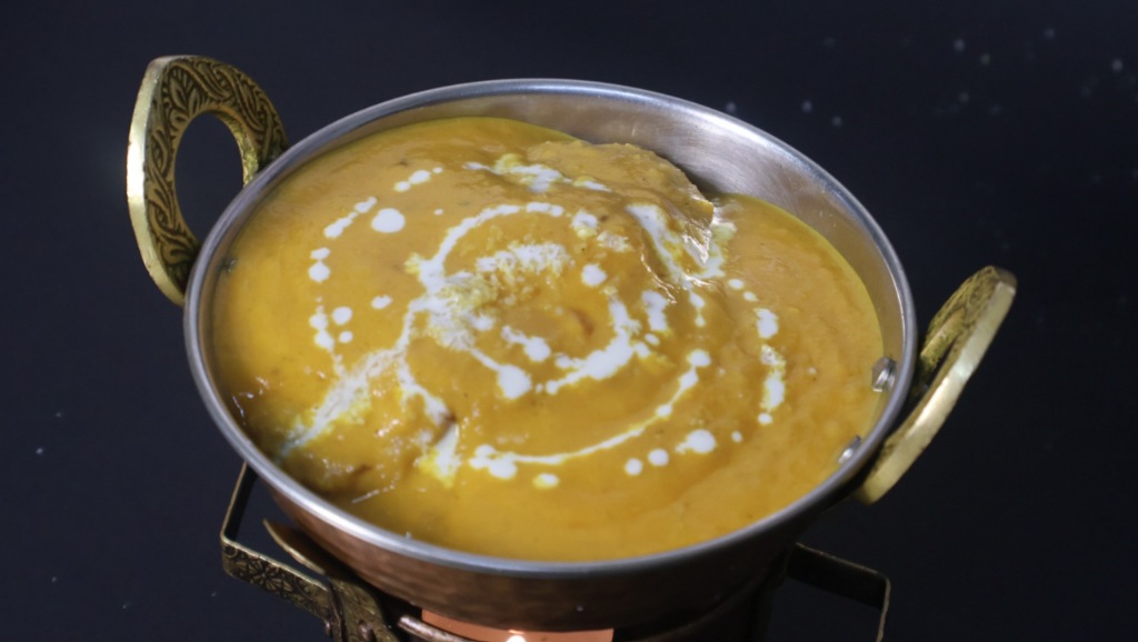 Rich, golden korma curry in a traditional metal bowl