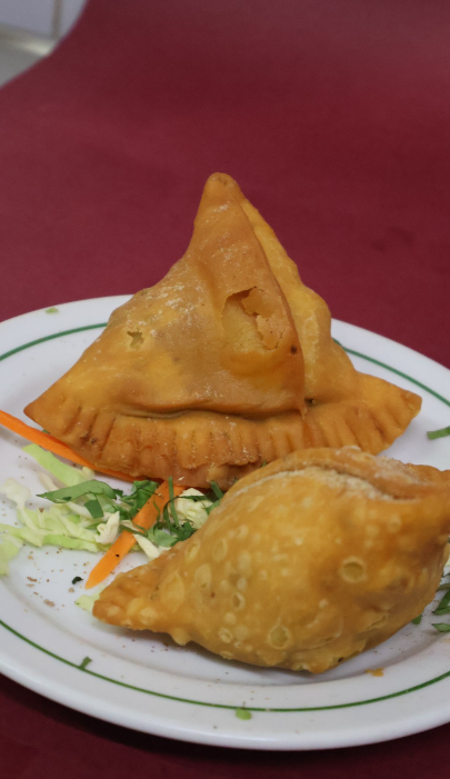 Crispy golden samosas served on a plate with garnishing